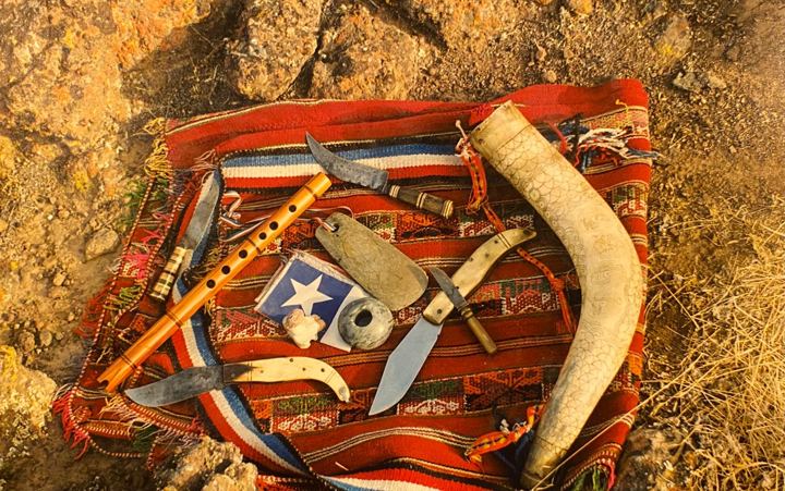 Flautas, cuchillos y un cuerno sobre un textil rojo